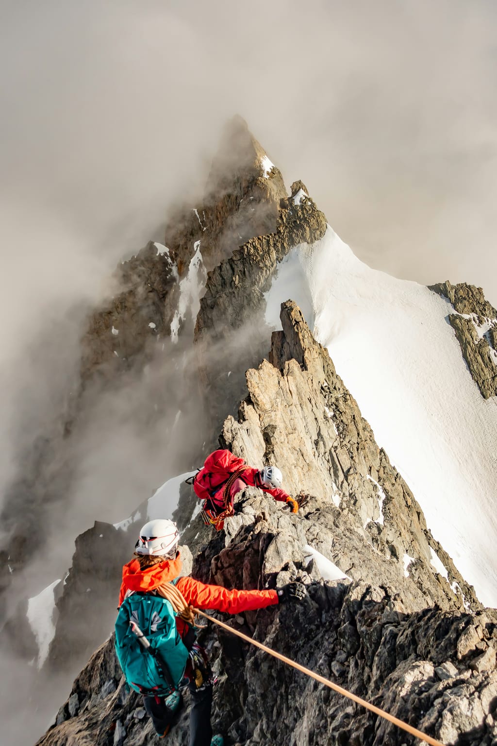Two roped climbers on a snowy ridge