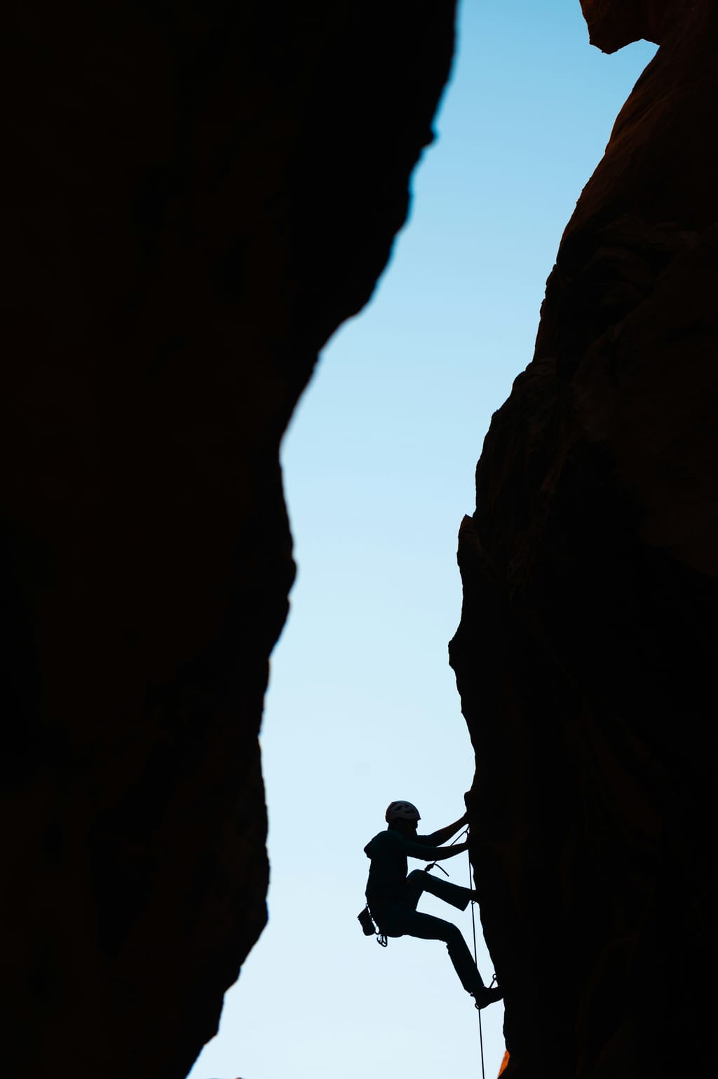Climber silhouetted in a narrow rock crevice