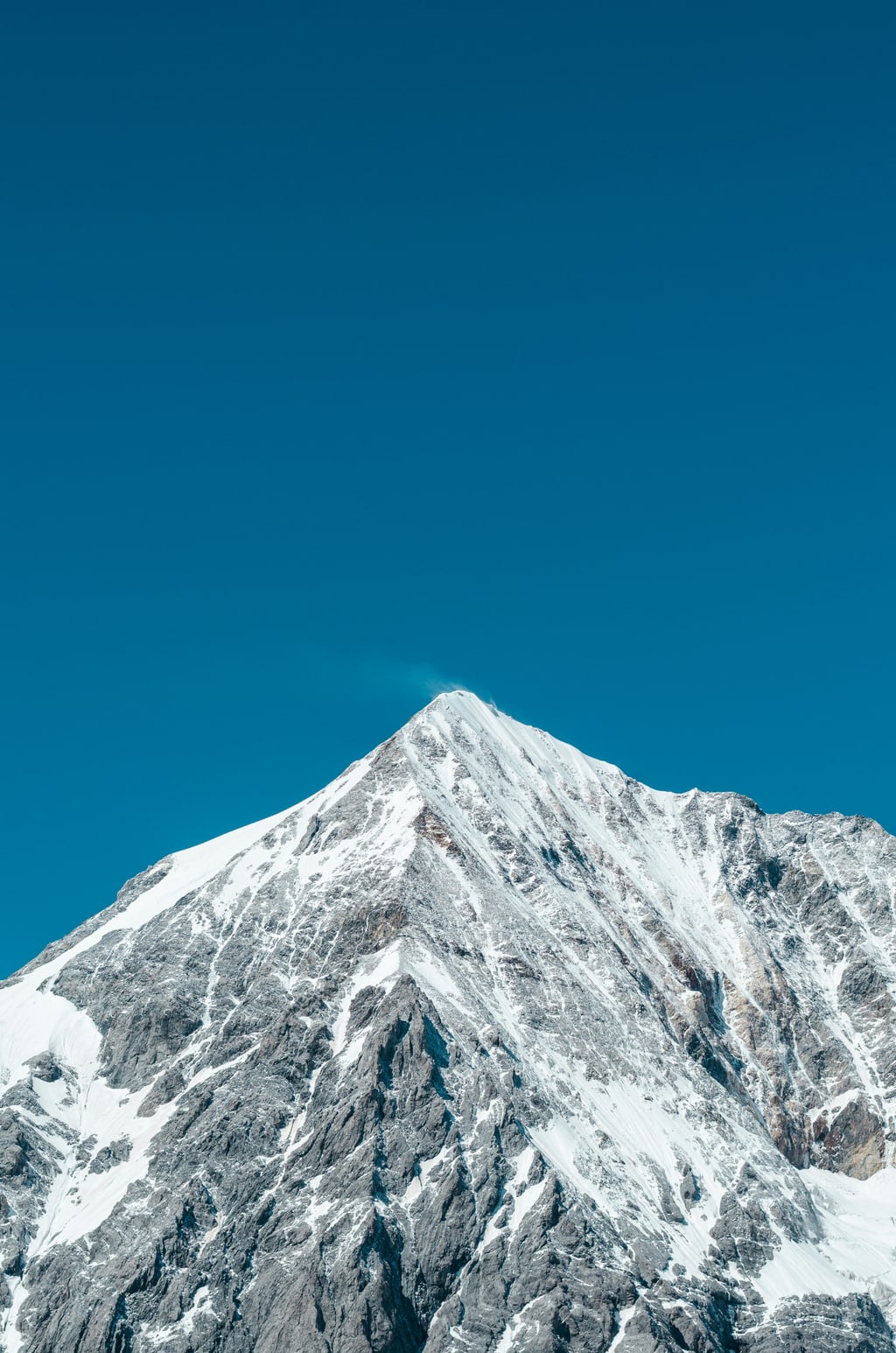 Snow-covered mountain peak against a deep blue sky