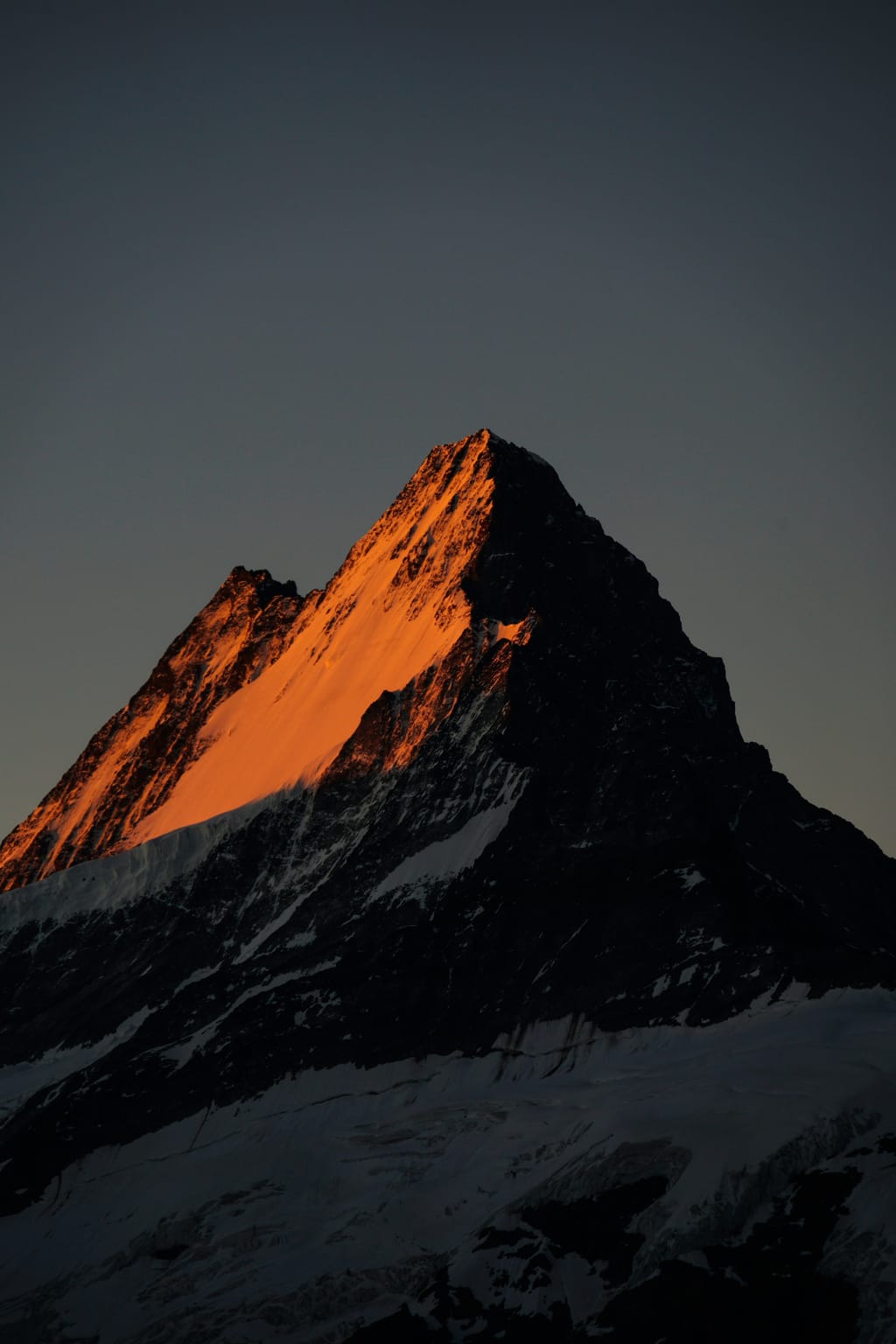 Mountain summit lit orange by the last sunlight